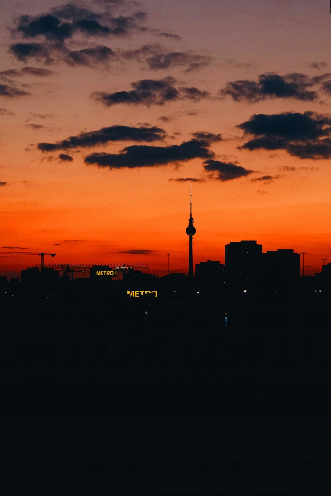 Une élégante berline noire garée la nuit sous un éclairage urbain.