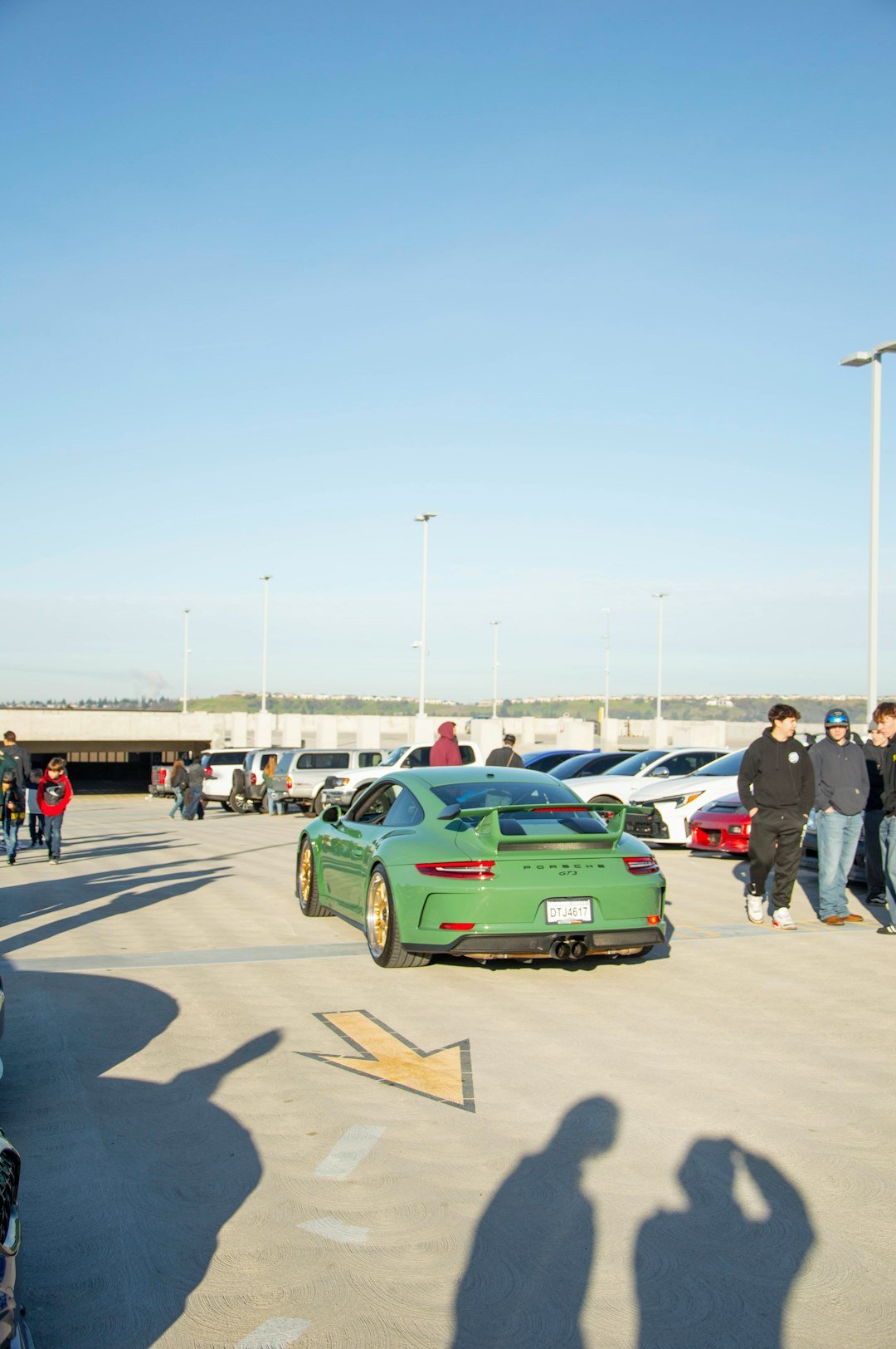 Un groupe diversifié de personnes discutant et souriant à côté de leurs voitures customisées lors d
