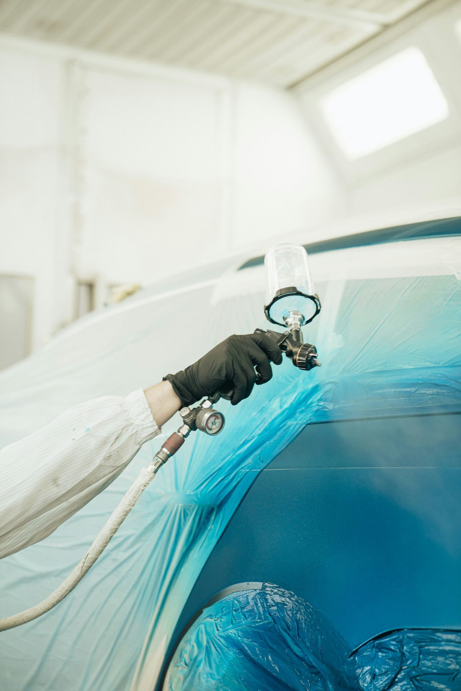 Detailer polishing a car hood in a professional workshop, focused on reflection and shine