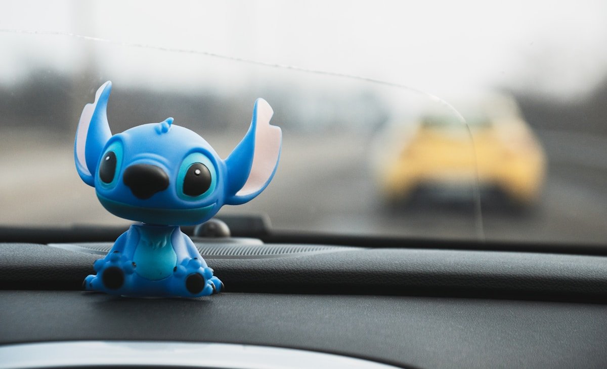 Stitch sits on a dashboard with a blurry car.