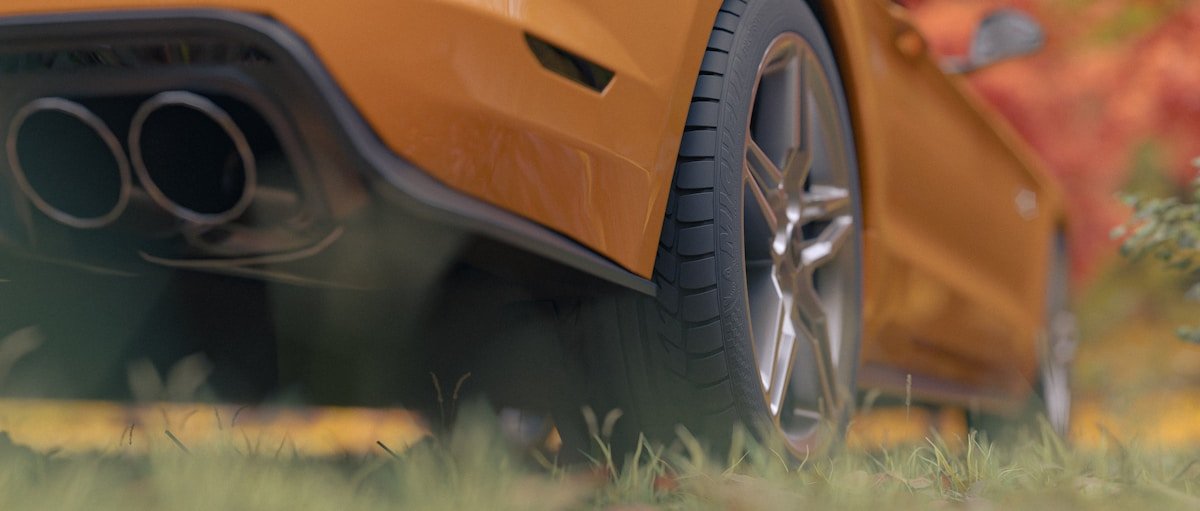 Exhaust pipes and wheel of a yellow car.