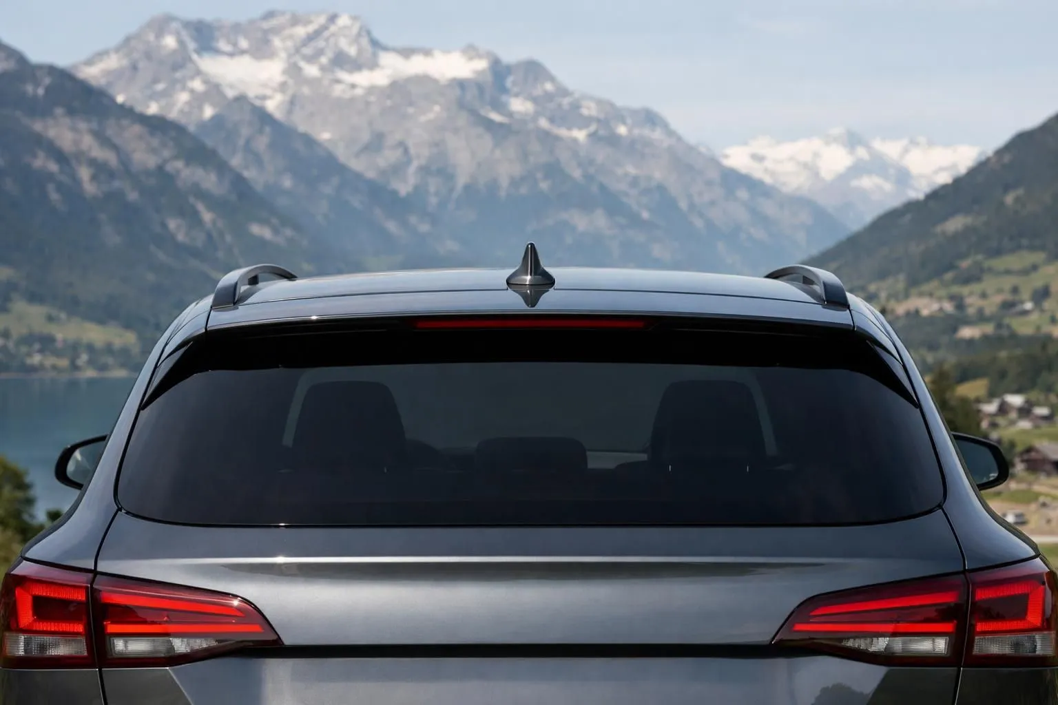 Close-up view of a modern car's rear section showing darkly tinted rear side windows and rear windshield with 100% tint, contrasting with lighter front windows, photographed in Swiss setting with mountains visible in background, professional automotive photography showing the legal customization freedom for rear windows