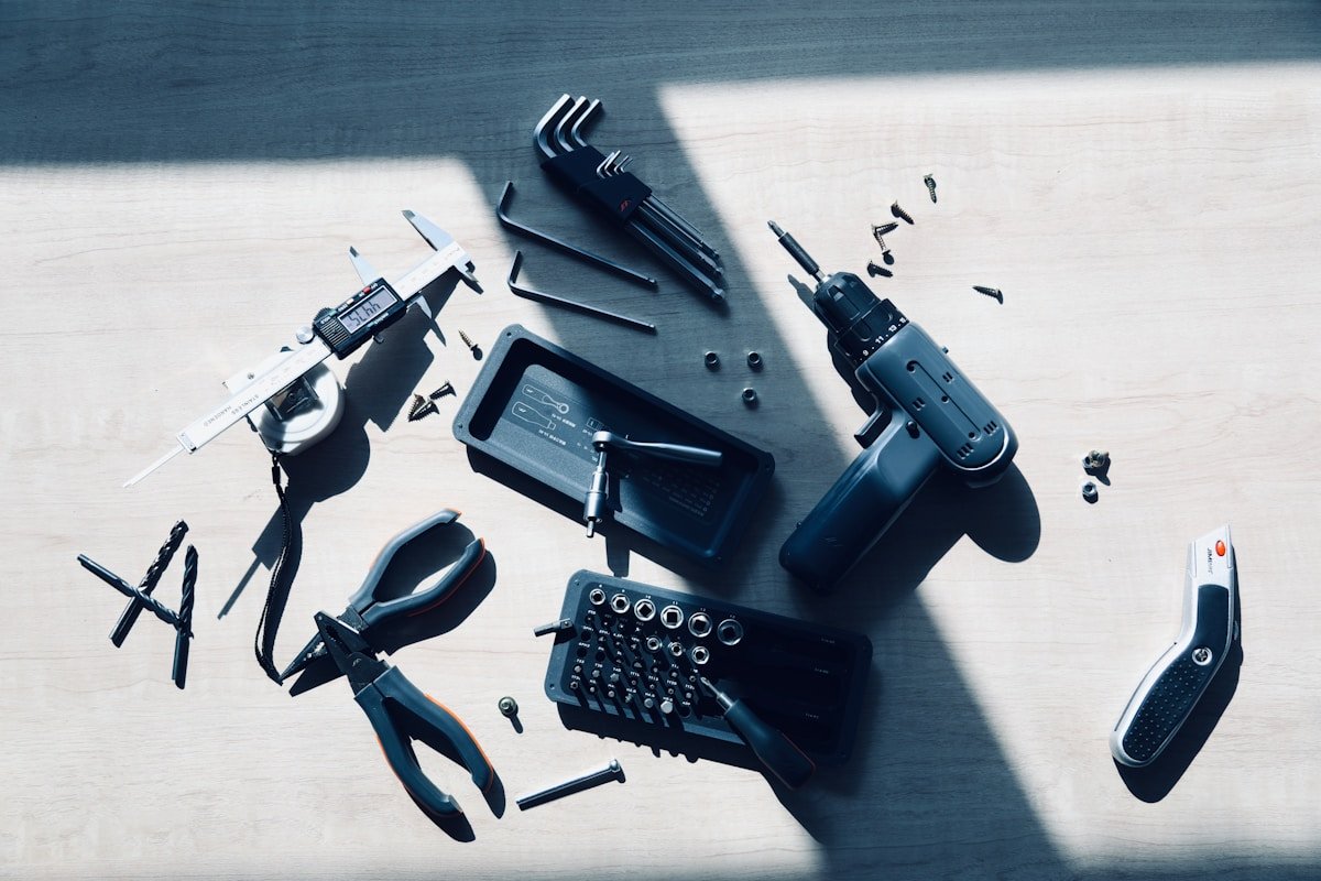 Outils de bricolage et accessoires électroniques sur une surface en bois.