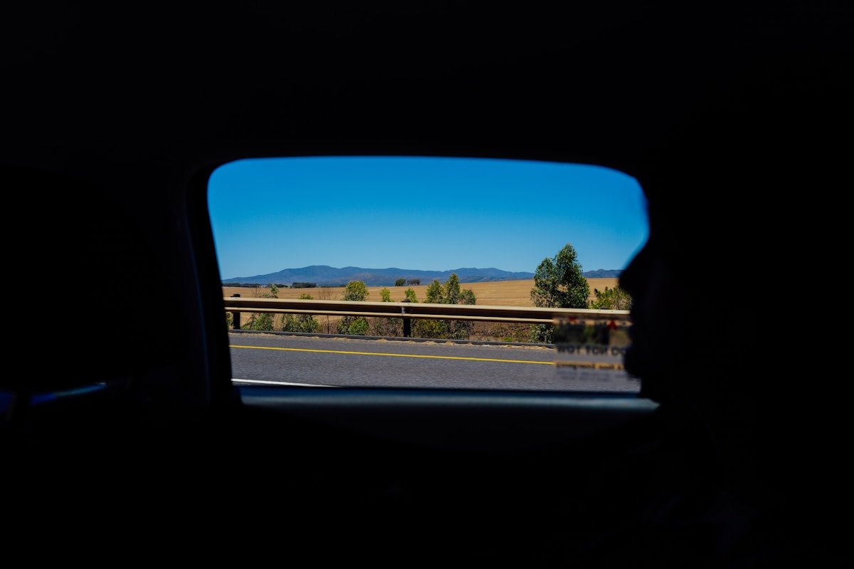 Paysage rural avec montagnes à l'horizon, vu depuis l'intérieur d'un véhicule.
