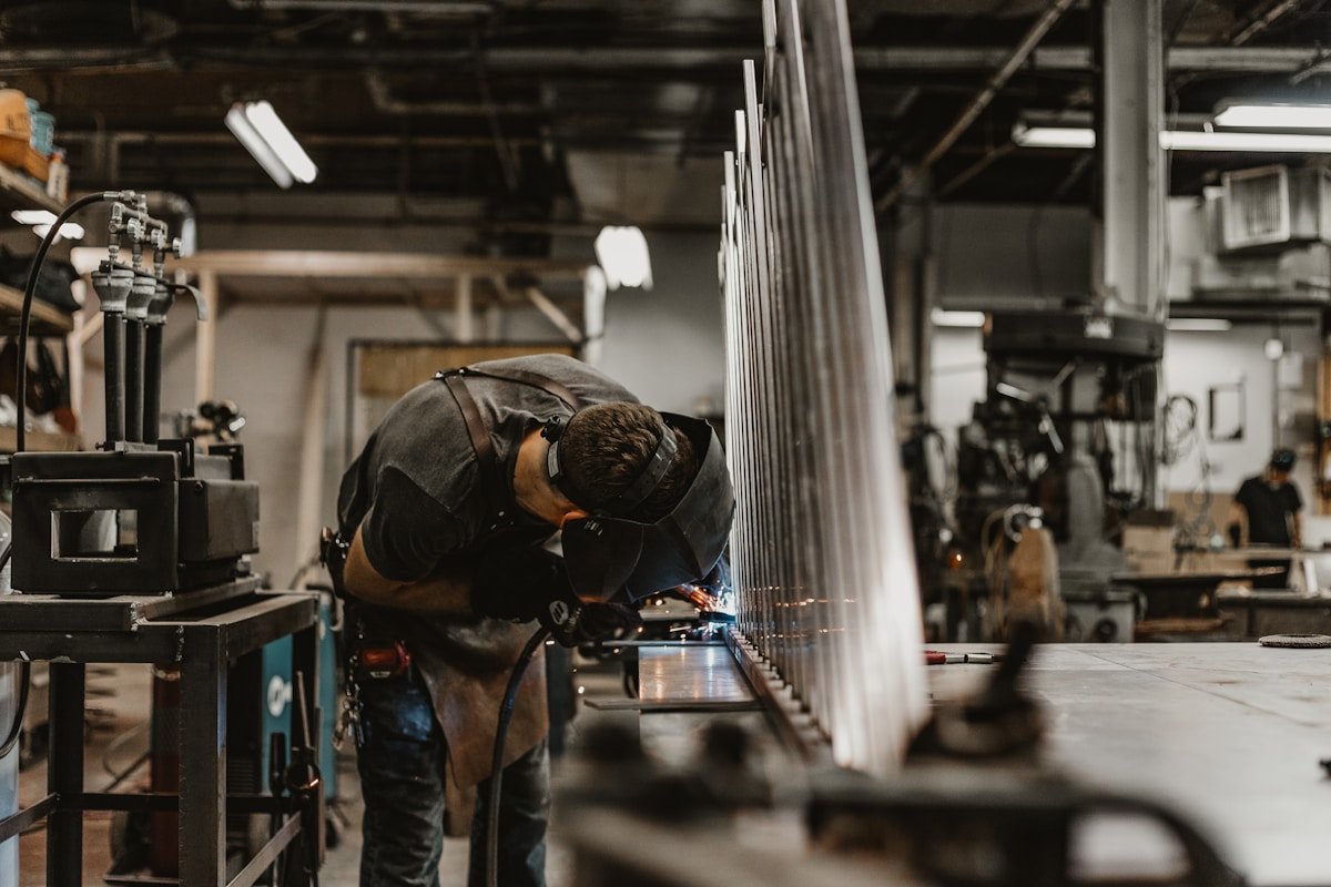 Homme travaillant avec un équipement de soudage dans un atelier industriel.