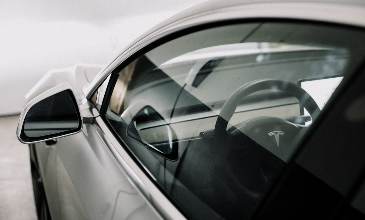 Intérieur d'une voiture électrique Tesla avec volant et rétroviseurs.