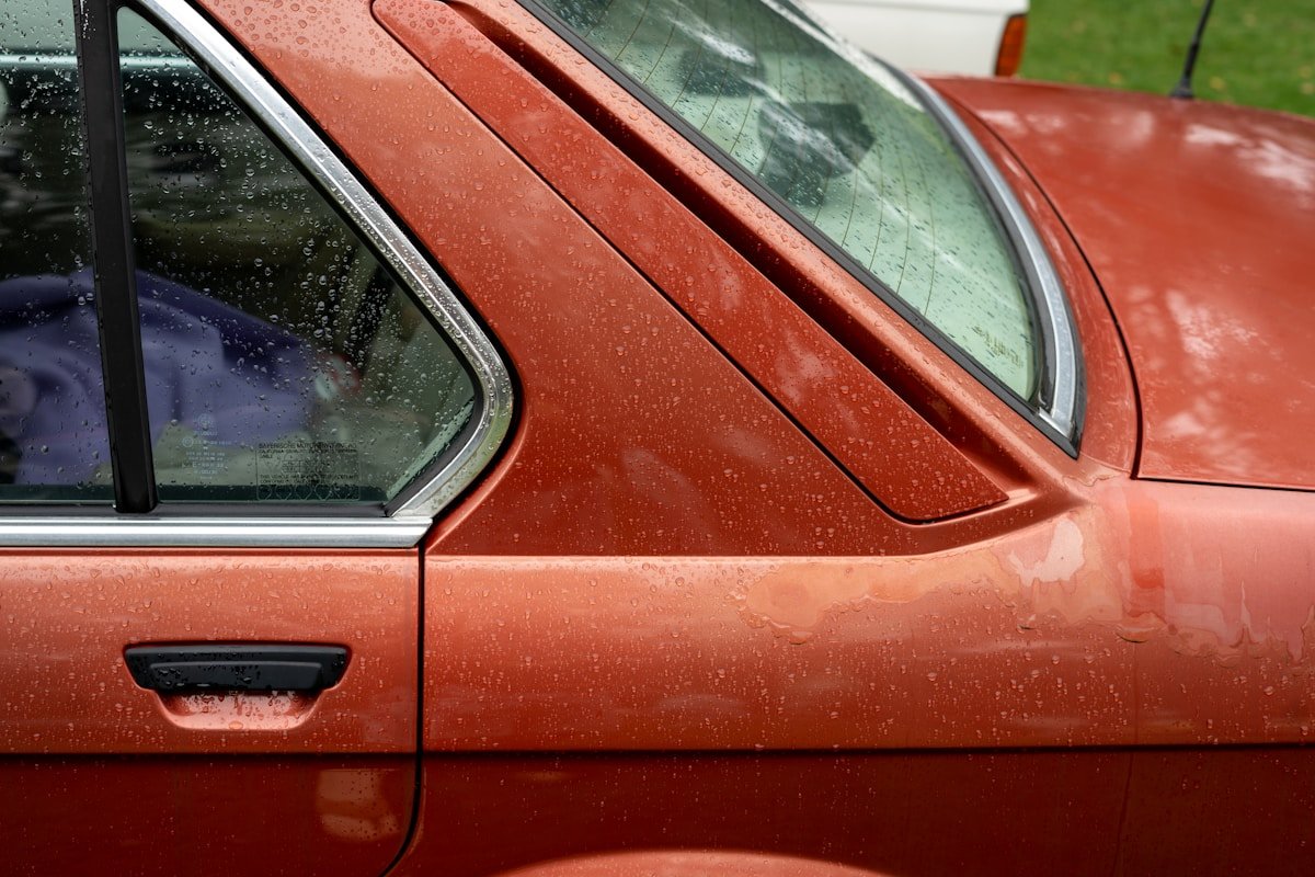 Un chien assis au volant d'une voiture rouge.