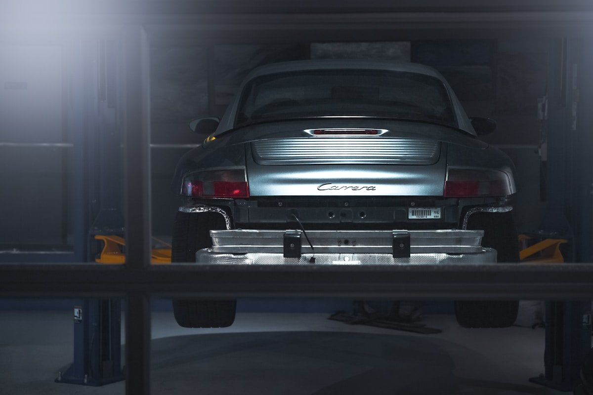 Voiture de sport Porsche Carrera dans un garage sombre et mystérieux.