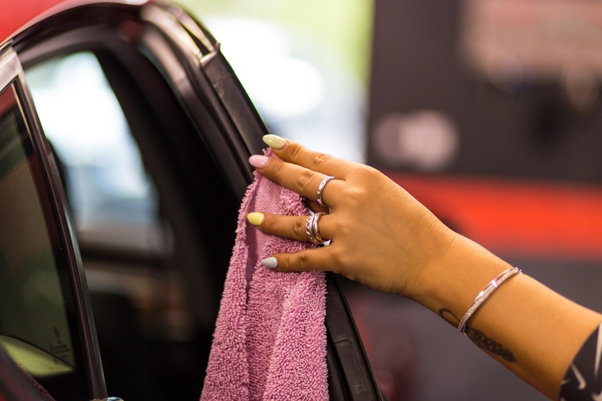 Mains féminines tenant un linge de toilette rose dans une voiture.