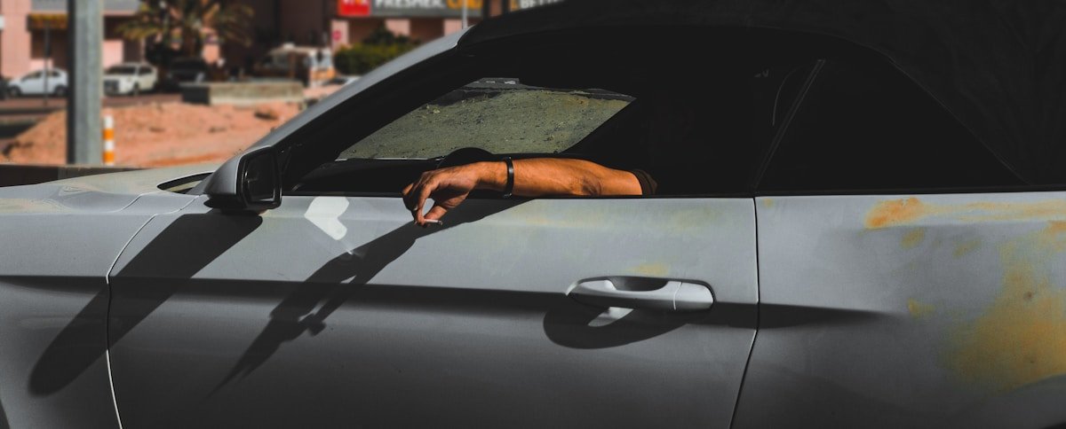 Gros plan d'une main sur le volant d'une voiture sombre.