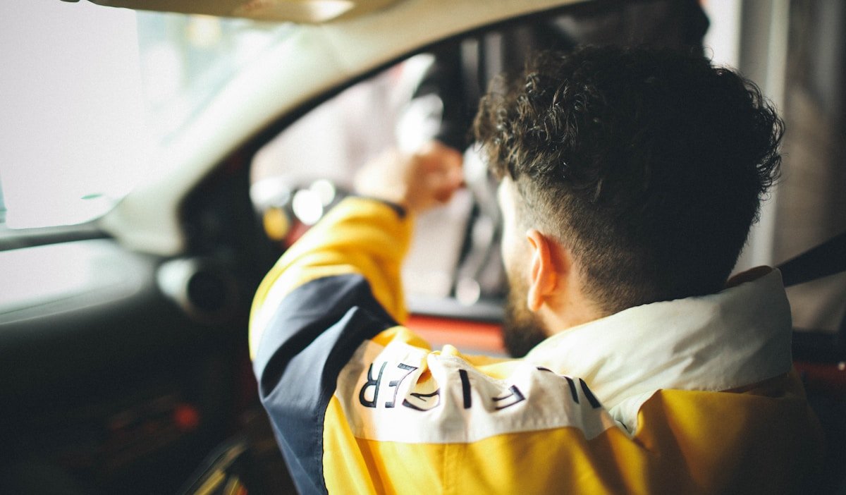 Homme en uniforme de travail conduisant un véhicule.