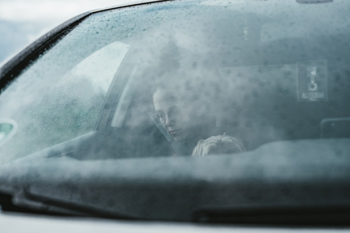 Visage flou d'une personne dans une voiture couverte de givre.