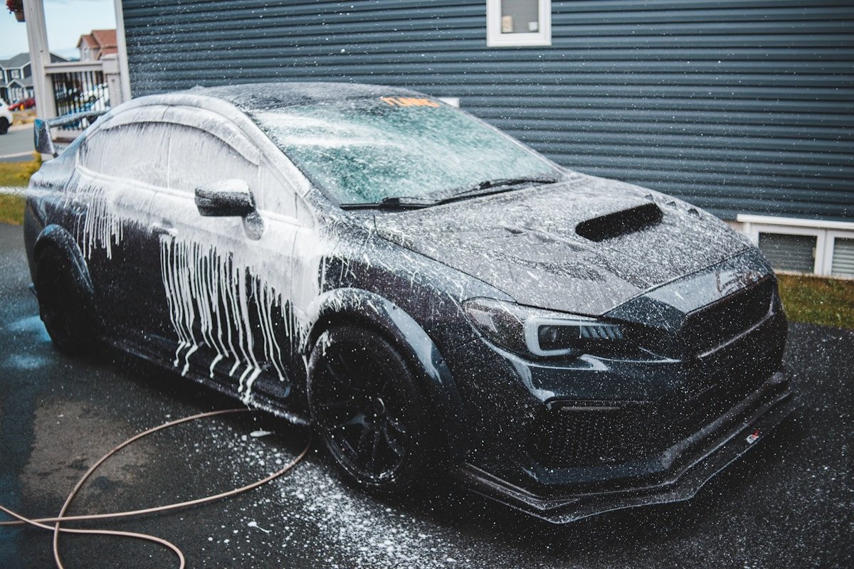Voiture noire couverte de glace et de neige, lavage de voiture par temps froid.