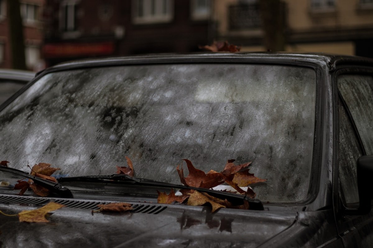 Voiture ancienne couverte de feuilles d'automne.