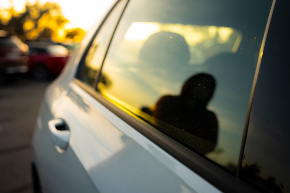 Reflet flou d'une silhouette dans le rétroviseur d'une voiture.