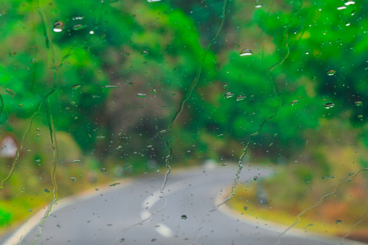 Pluie sur une fenêtre avec un arrière-plan flou et verdoyant.